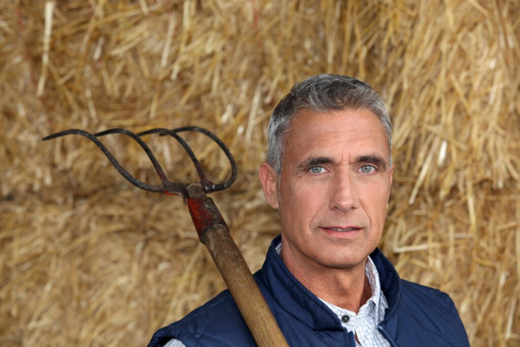 farmer holding pitchfork - this is one of the tools you can use when you decide how often to turn compost pile