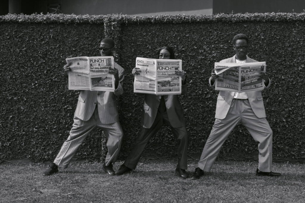 three people standing and reading newspapers - can you compost newspaper?