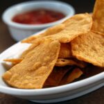 tortilla chips on a plate with a side of salse