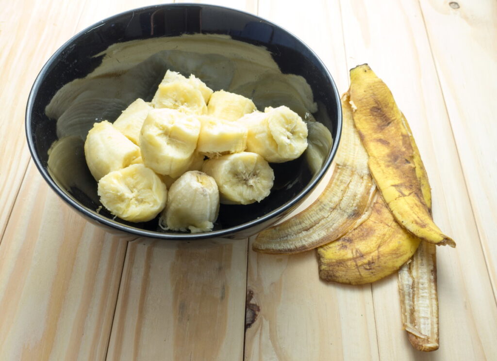 banana in black bowl with peels on wooden background can you compost banana