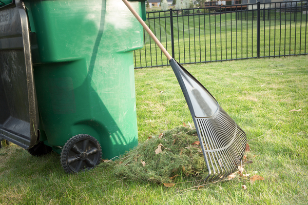 raking up grass clippings into compost bin