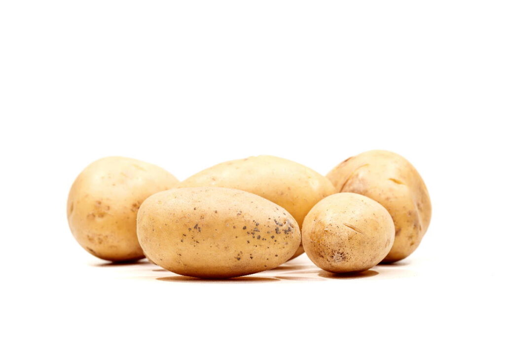 several whole potatoes on a white background - can you compost potatoes?