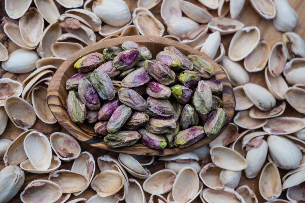pistachio nuts in brown bowl on bed of shells