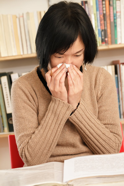 woman sneezing into facial tissue