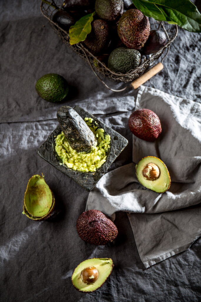 sliced avocado with a skin and a half with avocado pit in it